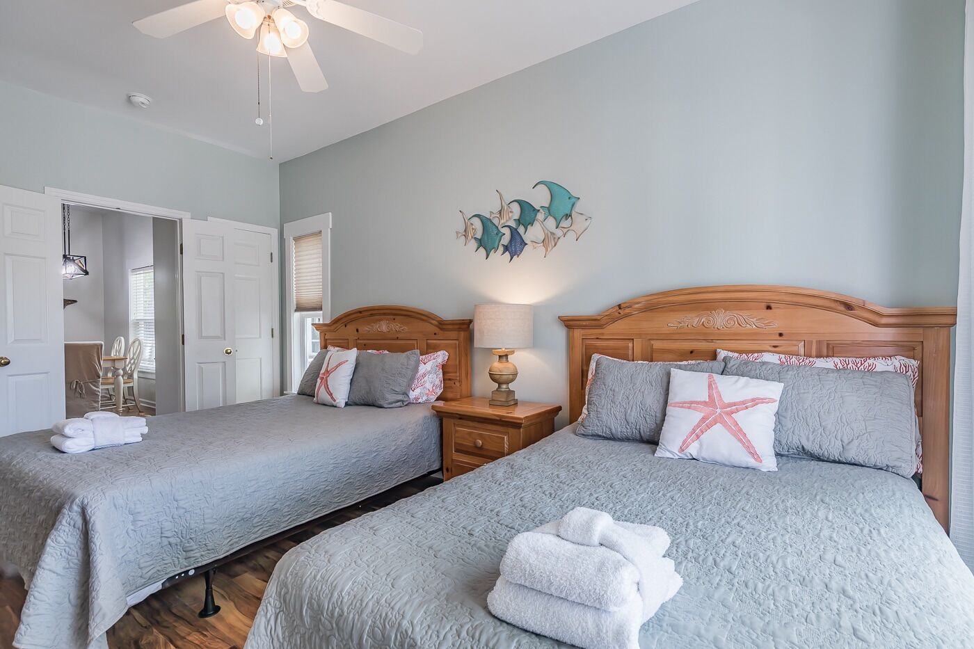A hotel room with two beds, a ceiling fan, and a wall art piece.