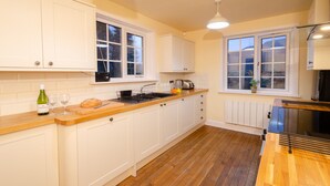 Une cuisine avec des meubles blancs, un plan de travail en bois, un four encastré et une fenêtre donnant sur un beau paysage.