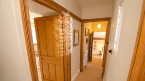 A hallway with a wooden door, carpeted floor, and framed pictures on the wall. - Juniper Grasmere - Juniper Cottage, Grasmere (Grasmere)