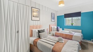 Una habitación de hotel moderna con dos camas, un armario y ventana con vistas.