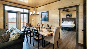 A wooden interior with a dining area, a sofa, and a bed. - New 5BR Cabin w/ Pool, Hot Tub • Near Smokies (Sevierville)