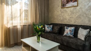 Una sala de estar con un sofá, una mesa de centro y un jarrón de flores.