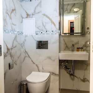 A bathroom with a toilet, sink, and mirror. - COOP Apartments (Sofia)