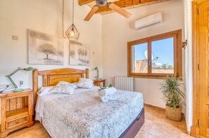 Una camera da letto con una testiera in legno, un letto con biancheria a motivi decorativi, una lampada a sospensione, una finestra con vista e un termosifone.