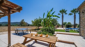 An outdoor patio with a ping pong table, a wooden table with drinks, and a pool area. - Mallorquin Finca piscina CA'S SOLLERICH en Mallorca (Inca)
