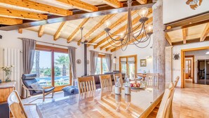 A spacious living area with a wooden ceiling, a glass dining table, and a view of the outdoors. - Mallorquin Finca piscina CA'S SOLLERICH en Mallorca (Inca)