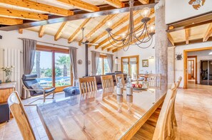 Un'ampia zona giorno con soffitto in legno, un tavolo da pranzo in vetro e vista sull'esterno.