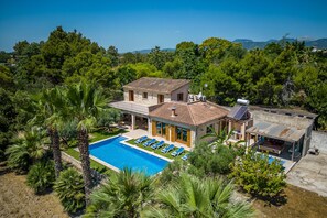 Una casa a due piani con piscina e un'area esterna coperta.