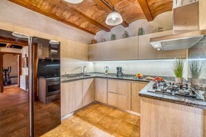 Una cocina moderna con armarios de madera, una estufa empotrada y una encimera con diversos objetos.