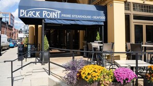The exterior of Black Point Prime Steakhouse with outdoor seating and a sign indicating it serves seafood. - Stately Executive Home with Modern Amenities (Columbus)