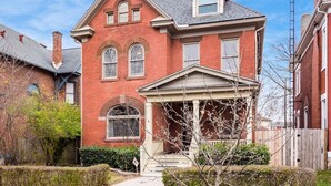 A two-story brick house with a gabled roof and a front porch. - Stately Executive Home with Modern Amenities (Columbus)