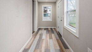 A hallway with a herringbone floor pattern, white walls, and two doors leading to outdoor areas. - Stately Executive Home with Modern Amenities (Columbus)