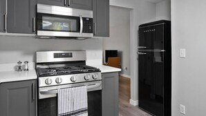 A modern kitchen with a built-in microwave, stove, and black refrigerator.