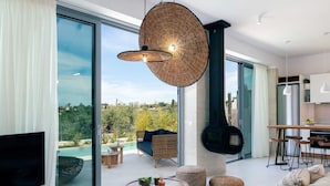 A modern living room with a large TV, a fireplace, and a dining area with a view of the outdoors. - NEW Lux Villa*Heated SaltyPool*BBQ*SeaView*Garden (Chania)