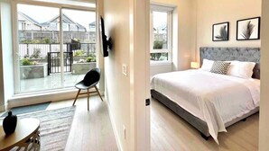 Een slaapkamer met een groot bed, een stoel en uitzicht naar buiten.