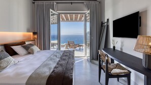 Une chambre d’hôtel moderne dotée d’un grand lit, d’un bureau et d’une télévision. La chambre offre une vue sur l’océan et dispose d’un balcon.