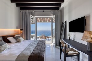 Een moderne hotelkamer met een groot bed, een bureau en een televisie. De kamer heeft uitzicht op de oceaan en een balkon.