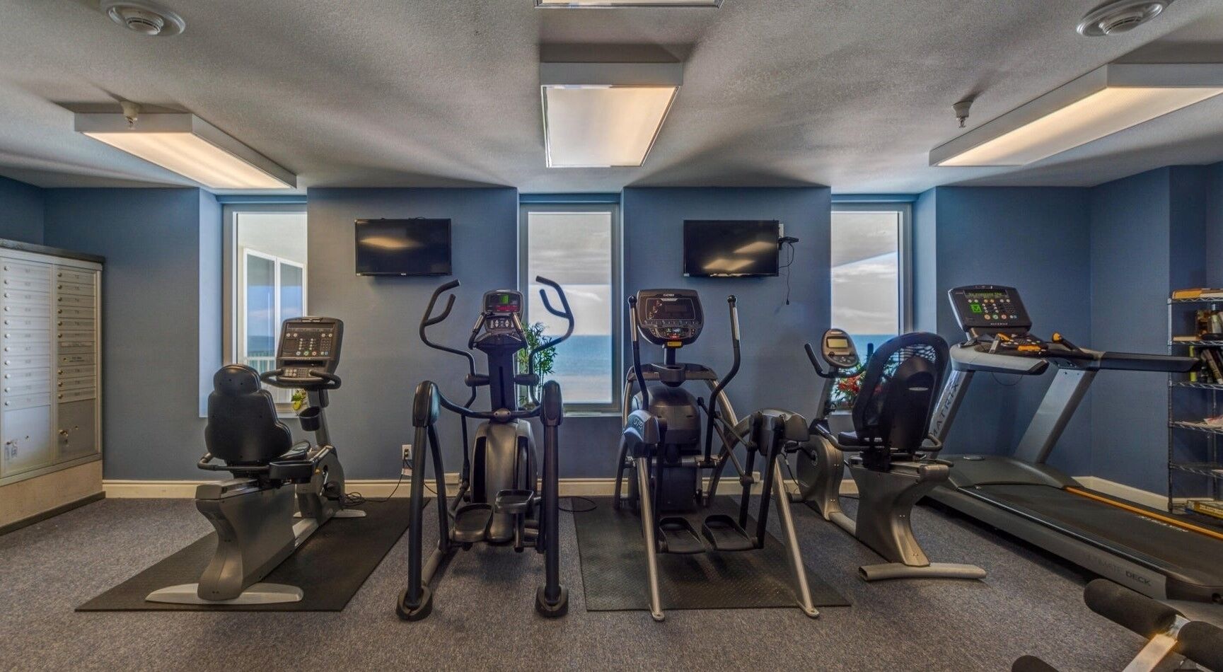 Un gimnasio con cintas de correr, elípticas y una bicicleta estática.