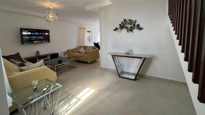 A modern living room with a sofa, coffee table, and TV. - Santo Domingo — Modern & Comfortable | 1 BR (Santo Domingo)