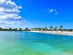 A beach with clear turquoise water, a sandy shore, and palm trees. - Santo Domingo — Modern & Comfortable | 1 bedroom (Santo Domingo)