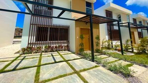 A modern two-story residential building with a flat roof, large windows, and a covered patio area. - Santo Domingo — Modern & Comfortable | 1 BR (Santo Domingo)