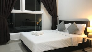 Una cama bien tendida con sábanas blancas y dos almohadas, una mesita de noche con una lámpara y una ventana con cortinas.
