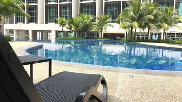 Un hotel moderno con piscina, palmeras y vistas a la fachada del edificio.