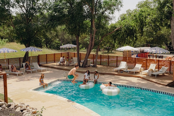 Una piscina al aire libre, sombrillas, sillones reclinables de piscina