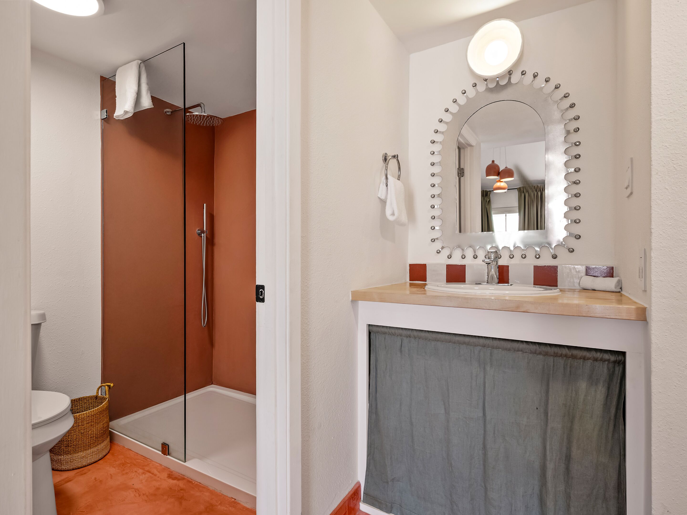 A bathroom with a glass shower enclosure, a sink with a vanity mirror, and a towel rack.