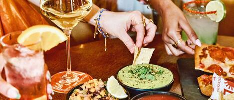 Una mesa con diversos platos, bebidas y una copa de vino blanco.