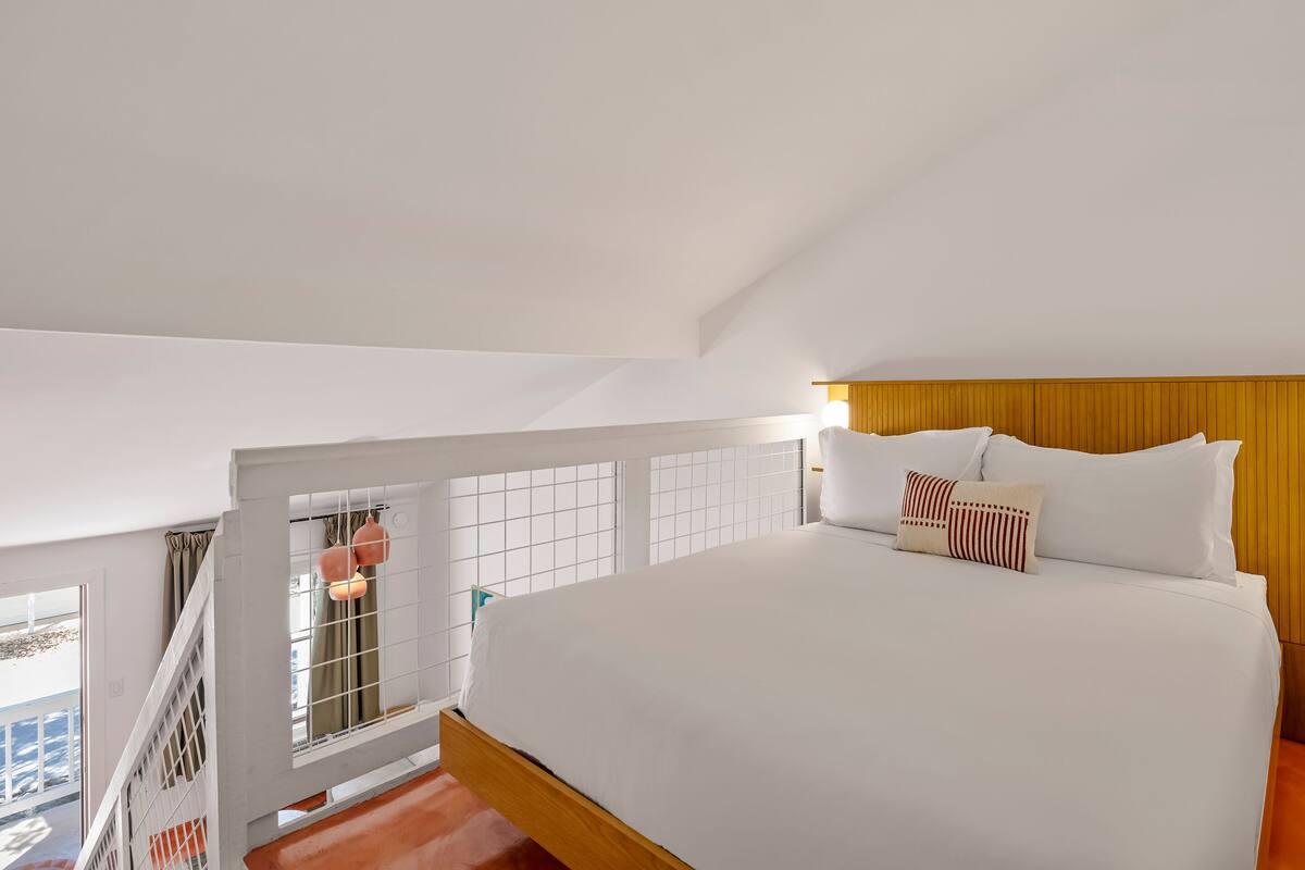 A bedroom with a large bed, a wooden headboard, and a view of the outdoors.