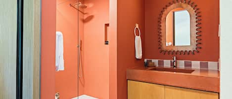 A bathroom with a shower, a sink, and a mirror.