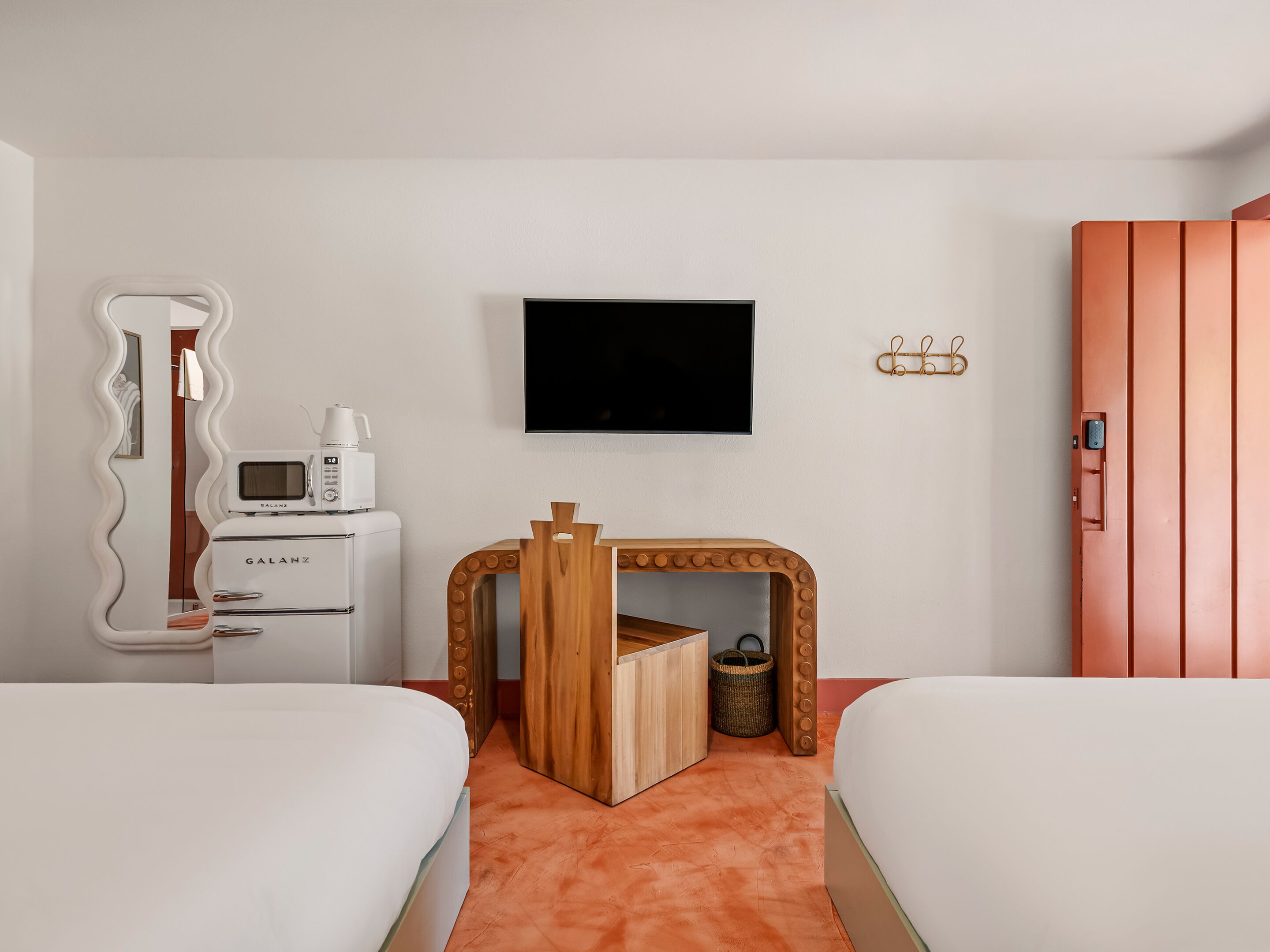 Habitación de hotel con dos camas, televisión, minibar y corralito de madera.