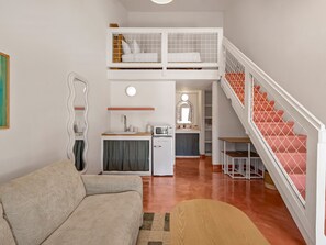 A compact living space with a kitchenette, a sofa, a dining area, and a staircase. - Hacienda del Rio (New Braunfels)