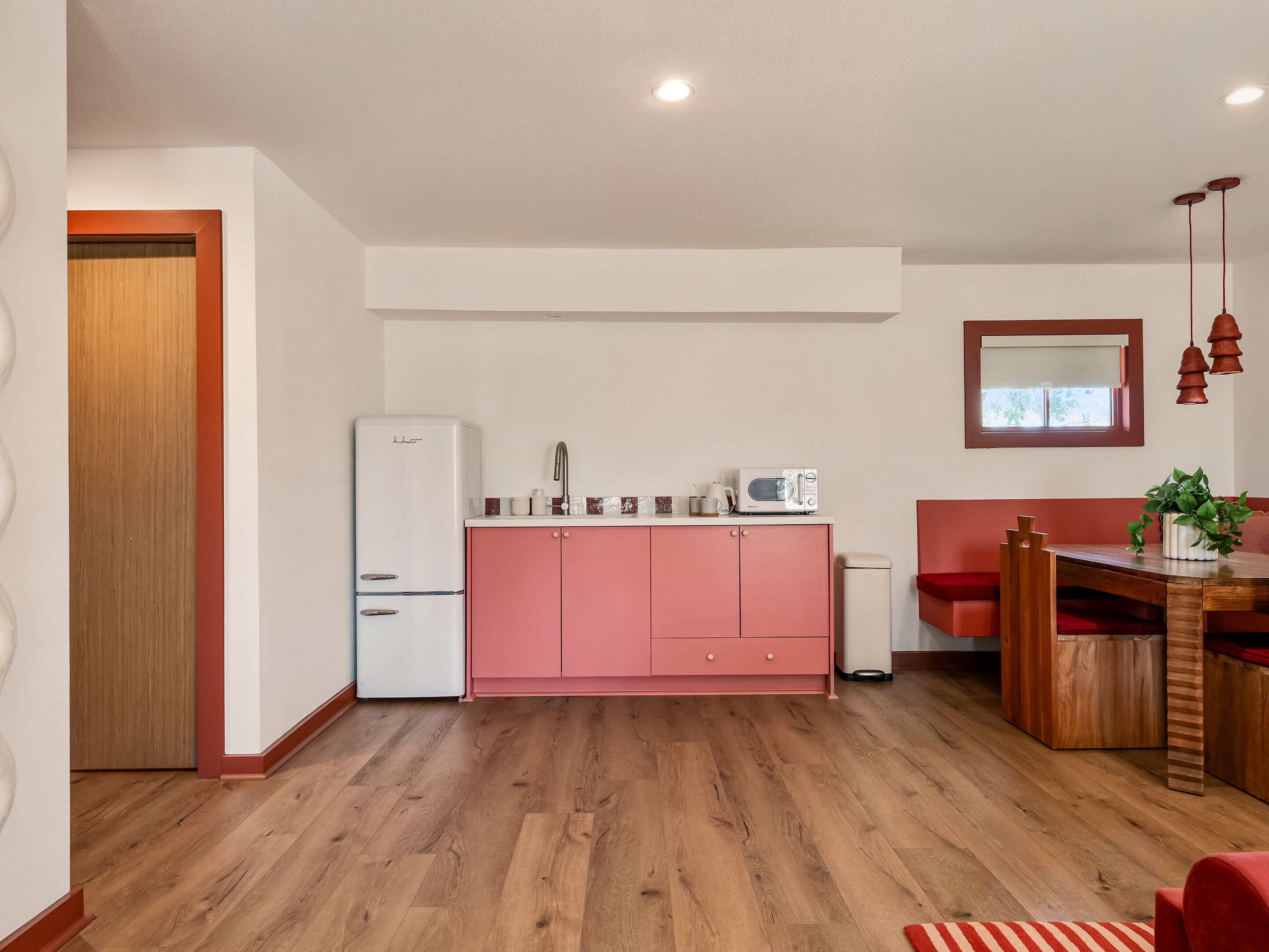 A compact kitchen with a refrigerator, microwave, sink, and a dining area with a table and chairs.