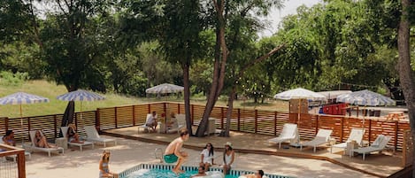 Una piscina al aire libre, sombrillas, sillones reclinables de piscina