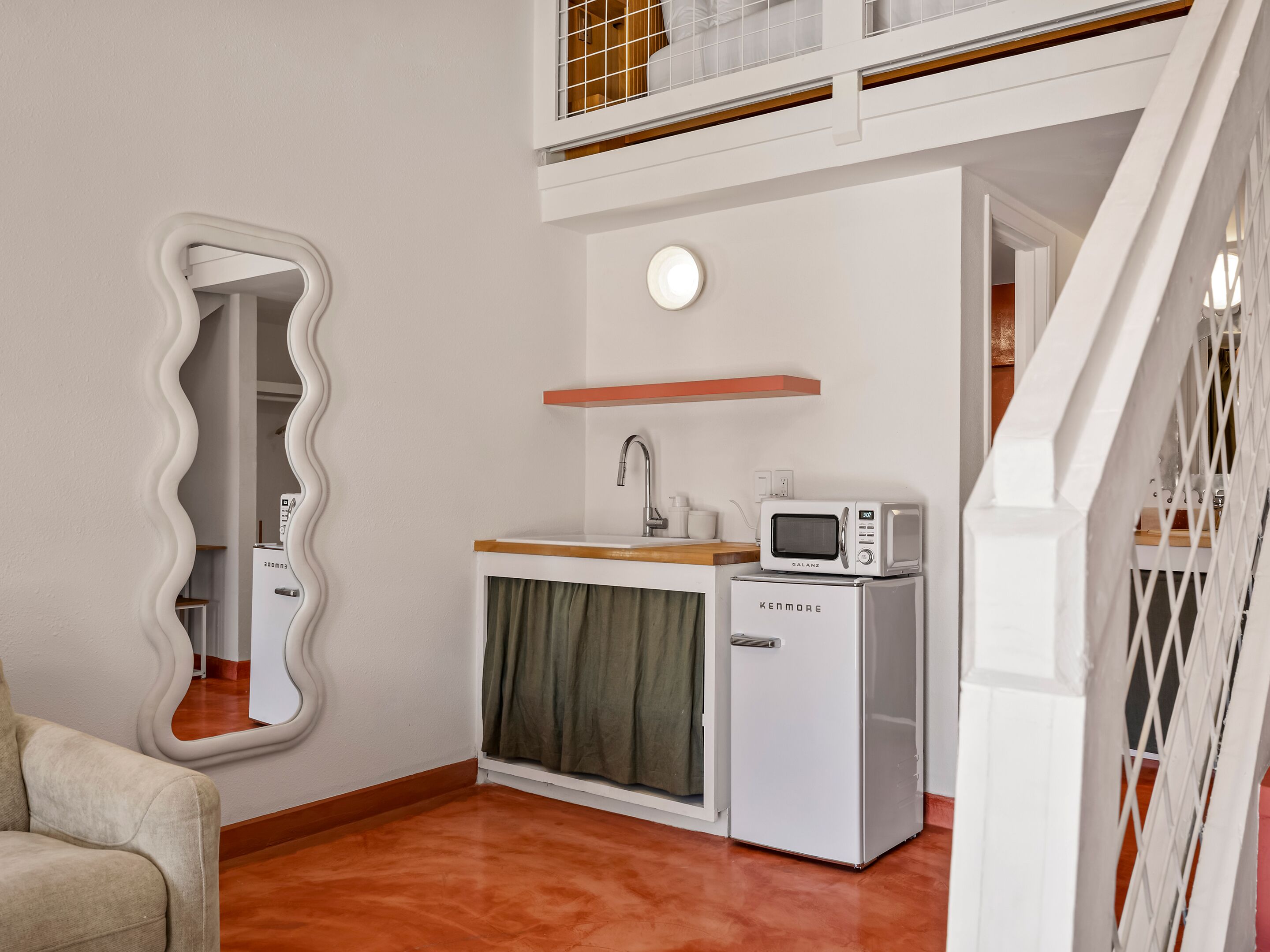 A compact kitchenette with a microwave, sink, and a small refrigerator.