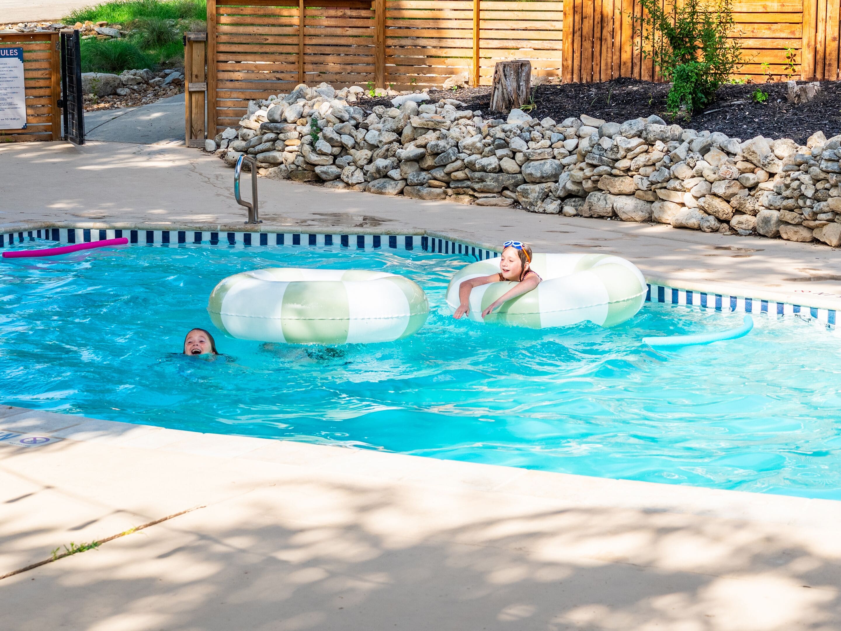 Una piscina al aire libre, sombrillas, sillones reclinables de piscina