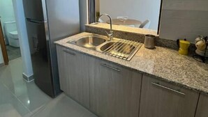 A modern kitchen with a stainless steel sink, a built-in oven, and a large mirror above the countertop. - Home The Good | cana view (Punta Cana)