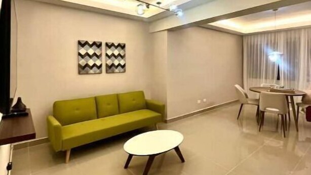 A modern living room with a green sofa, a round coffee table, and a dining area with a table and chairs. - Home The Good | cana view (Punta Cana)