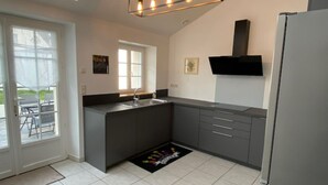 Une cuisine moderne dotée d’un îlot central intégré, d’une grande fenêtre et d’un téléviseur à écran plat fixé au-dessus de l’îlot.