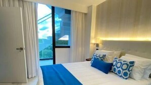 Una habitación de hotel moderna con una cama grande, un ventilador de techo y vistas al exterior.