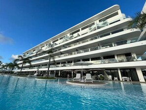 Een hotel met meerdere verdiepingen, met een zwembad en balkons met buitenmeubilair.