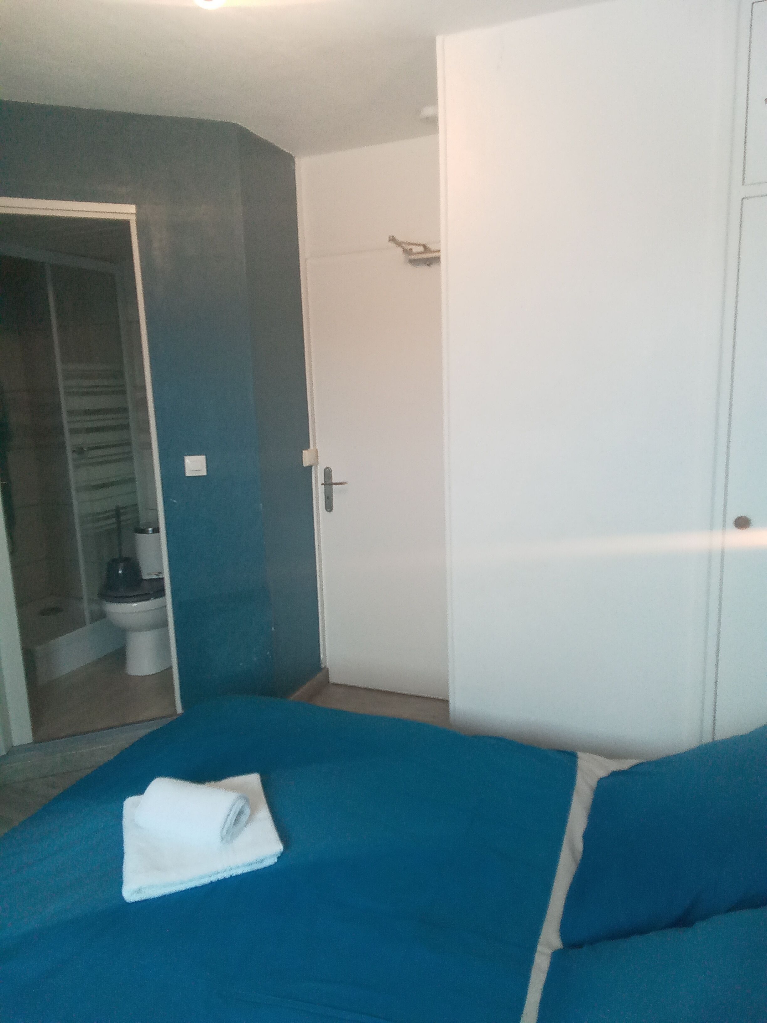 Een slaapkamer met een bed, een kledingkast en een badkamer die door een geopende deur zichtbaar is.
