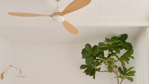Ein Schlafzimmer mit einem Bett, einem Deckenventilator, einer Nachttischlampe und einem Blumentopf.