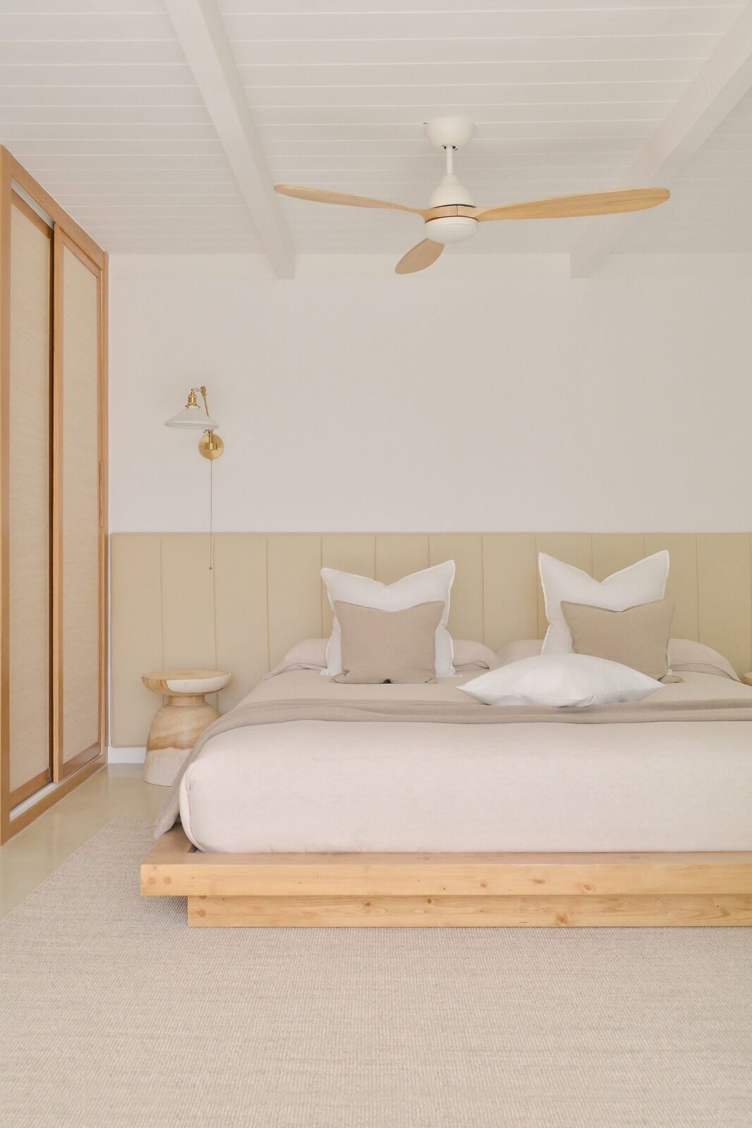 Une chambre avec un lit en bois, un ventilateur de plafond et une table de chevet.