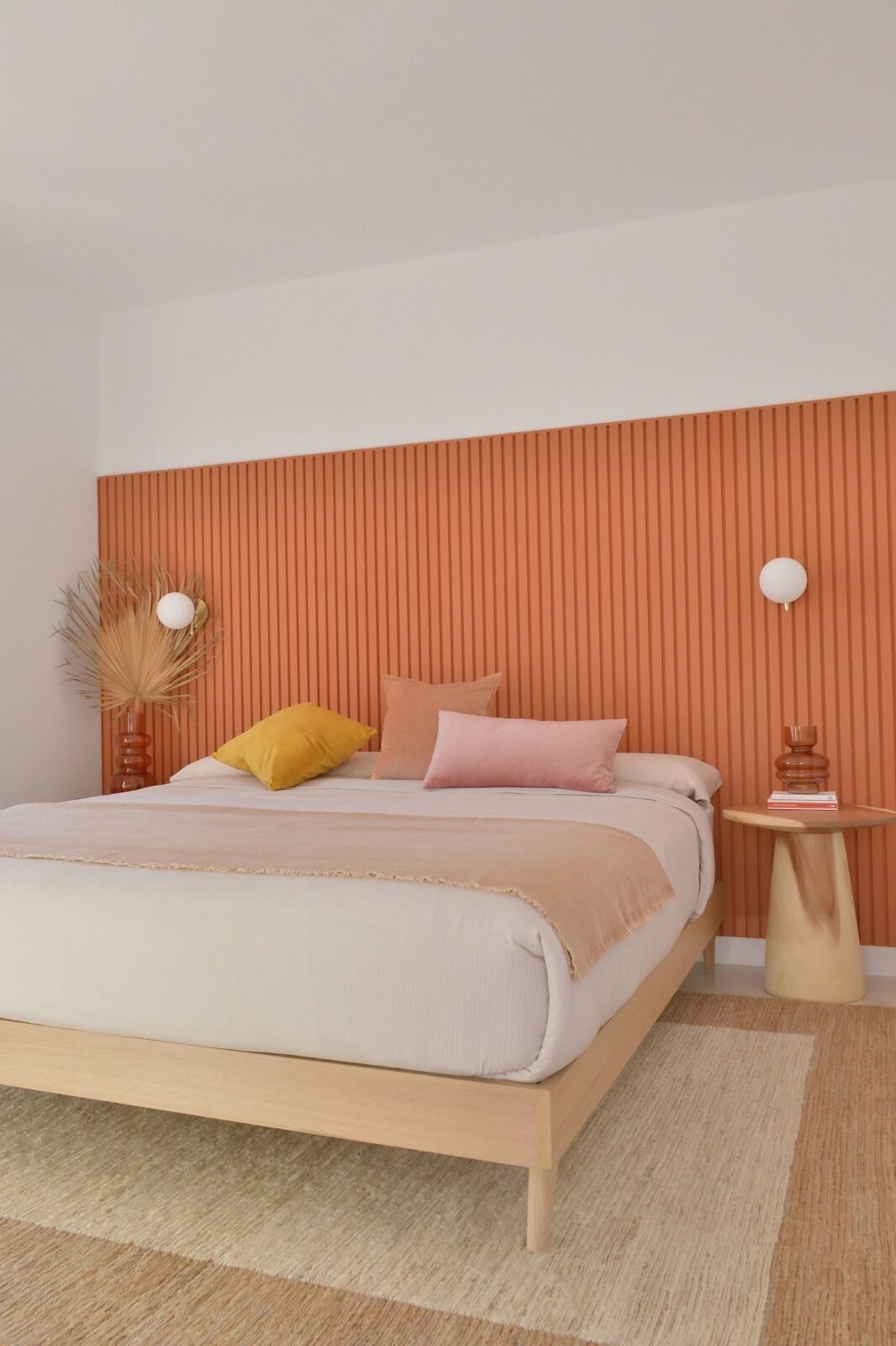 Quarto moderno com cama, mesa de cabeceira e parede com linhas verticais.
