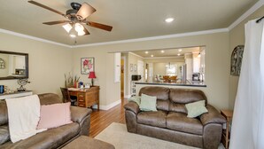 A living room with a brown leather sofa, a wooden coffee table, and a ceiling fan.