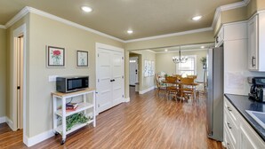 A spacious kitchen with wooden flooring, white cabinetry, and a dining area with a chandelier.