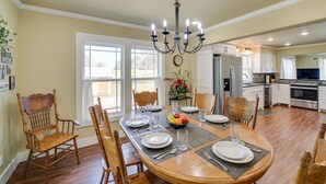 A dining area with a wooden table set for four, surrounded by wooden chairs.